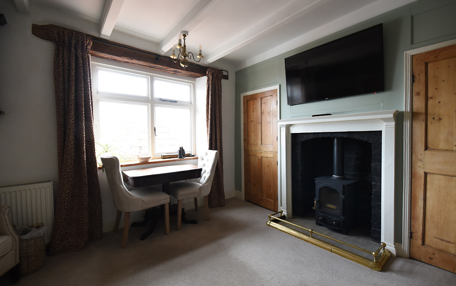 Living room with smart TV mounted over the fire place, chairs nest the window, Large timber lintel over the window