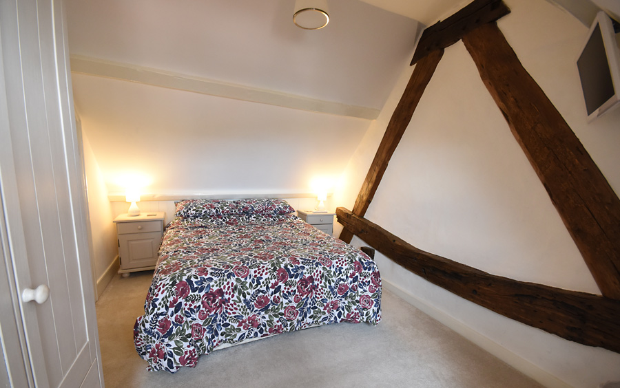 Bedroom wall with embedded timbers of previous roof structure principle rafters in an upper cruck style