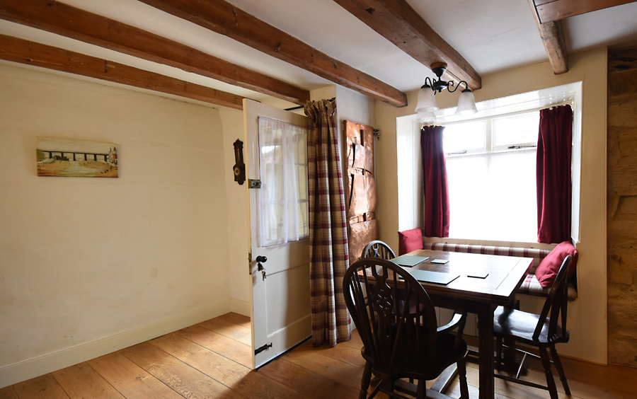Upholstered window seat, oak table and unique beaten copper radiator sculpted to suggest ships sails 