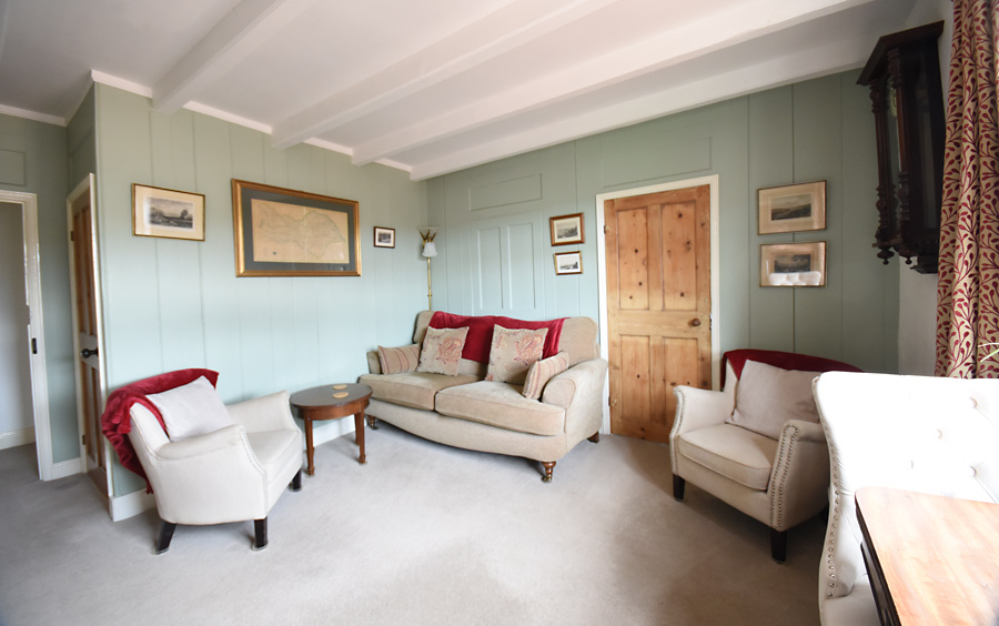 Living room comfortable settee and chairs old maps and pictures on the walls, door through to the bathroom