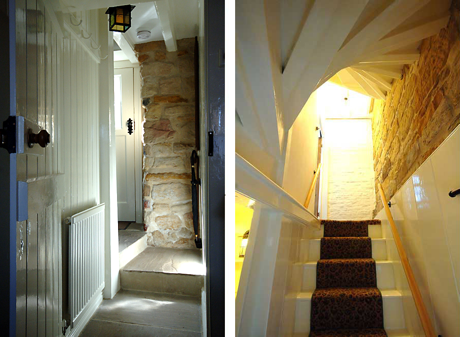 Hallway wit paneled and stone walls coat hooks over the radiator, strait stairs with the underside and the spiral stairs above 