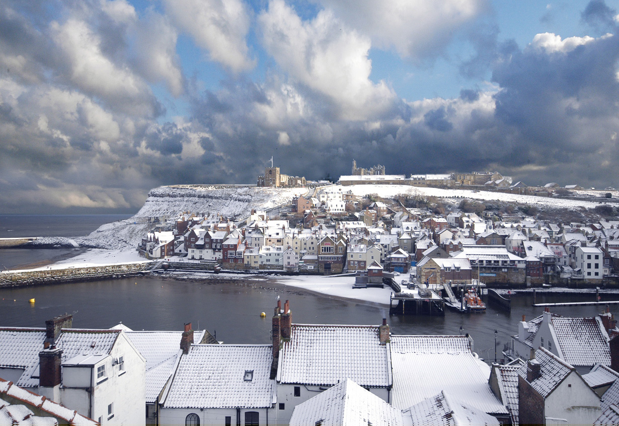 A rare Snowy Whitby with a dramatic winter sky and snow laden roofs
