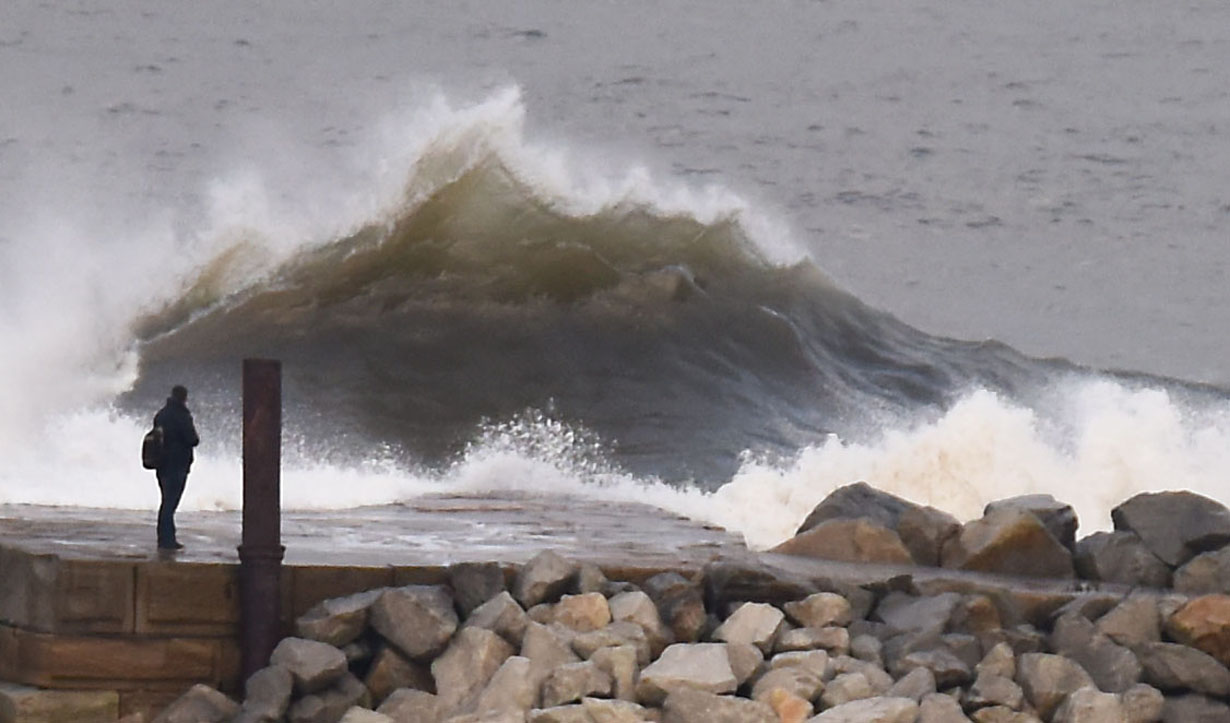 Watching waves crashing over the Harbour wall from the comfort and safety of a Holiday Cottage