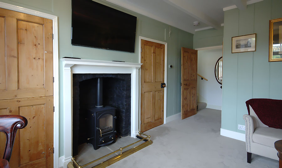 Living room witha largely intact 18th centuary vertical timber paneled walls and four paneled doors, Wood stove in the fireplace